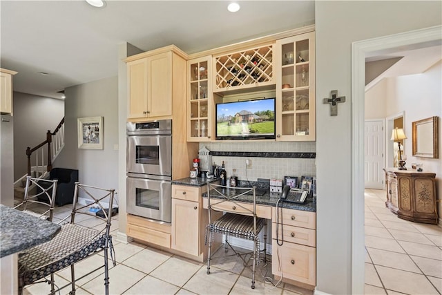 kitchen with backsplash, light tile patterned floors, a breakfast bar area, and appliances with stainless steel finishes