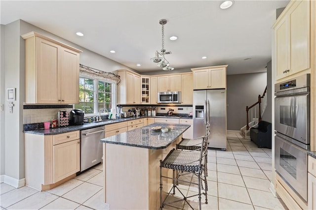 kitchen featuring dark stone counters, decorative backsplash, light tile patterned floors, appliances with stainless steel finishes, and a kitchen island