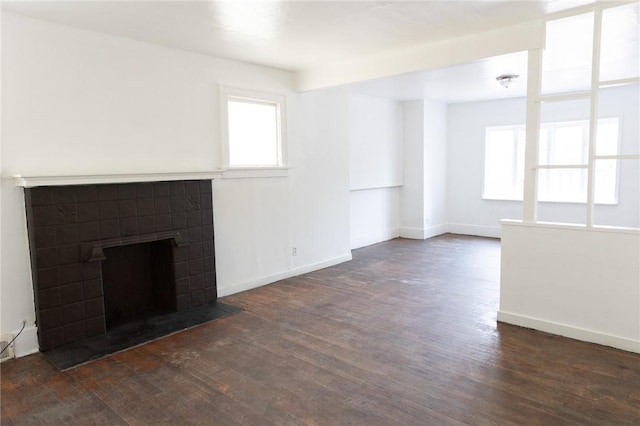 unfurnished living room featuring dark wood-type flooring and a tile fireplace