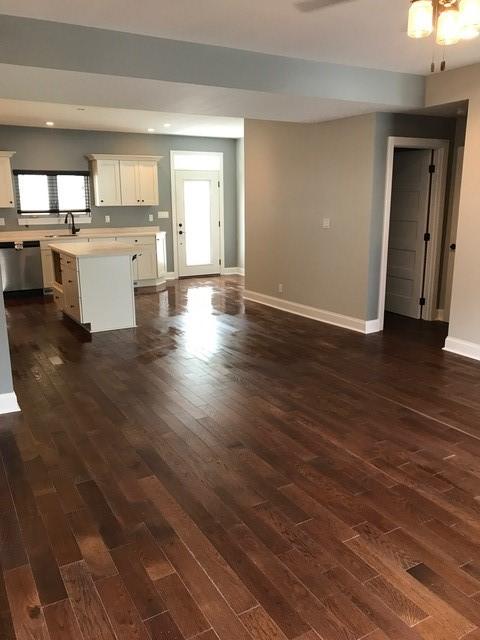 unfurnished living room with dark hardwood / wood-style floors, ceiling fan, and sink