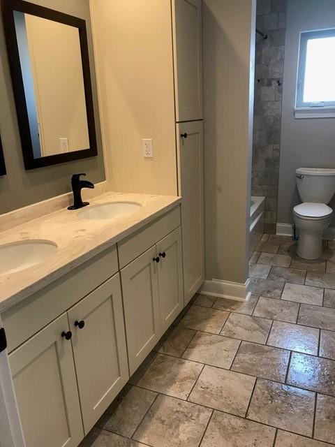 full bathroom with vanity, tiled shower / bath combo, and toilet