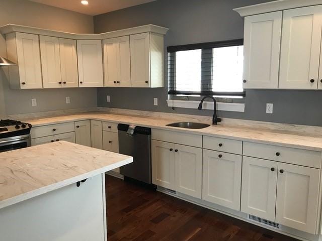 kitchen with appliances with stainless steel finishes, light stone counters, sink, white cabinets, and dark hardwood / wood-style floors