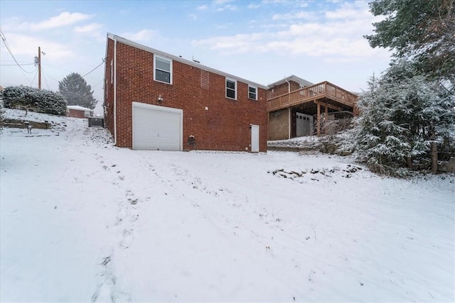 snow covered property featuring a garage and a wooden deck