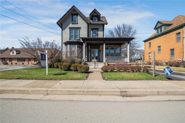 victorian house featuring a porch and a front yard