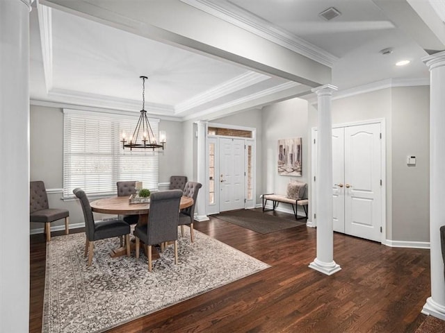 dining room featuring an inviting chandelier, a raised ceiling, dark hardwood / wood-style flooring, decorative columns, and crown molding