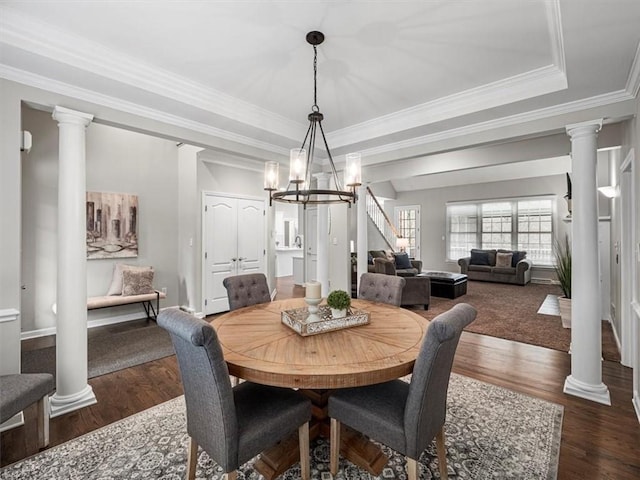 dining space featuring a tray ceiling, ornamental molding, dark wood-type flooring, and a notable chandelier