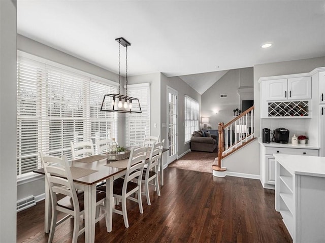 dining space featuring dark wood-type flooring, vaulted ceiling, and a notable chandelier