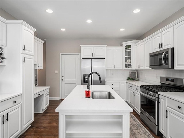 kitchen with appliances with stainless steel finishes, white cabinetry, a kitchen island with sink, and sink