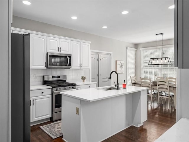 kitchen with pendant lighting, white cabinets, stainless steel appliances, and sink