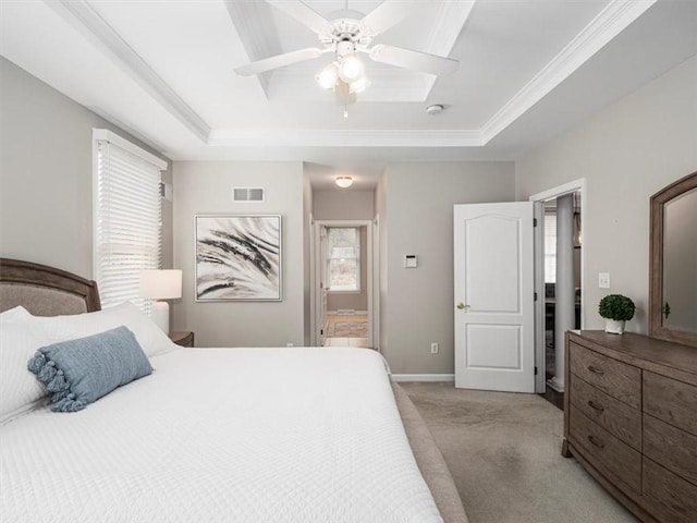 carpeted bedroom with a tray ceiling, multiple windows, ceiling fan, and ensuite bathroom