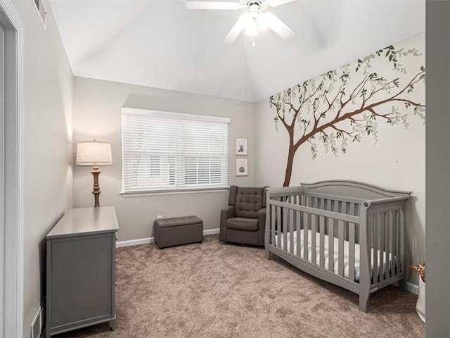 bedroom with vaulted ceiling, ceiling fan, light carpet, and a crib