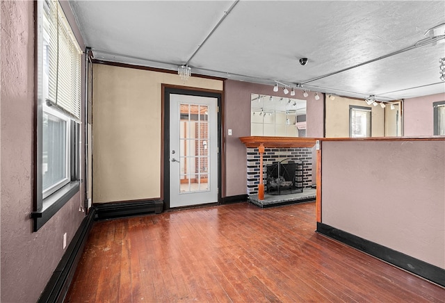 interior space featuring a baseboard radiator, a fireplace with raised hearth, baseboards, and wood finished floors