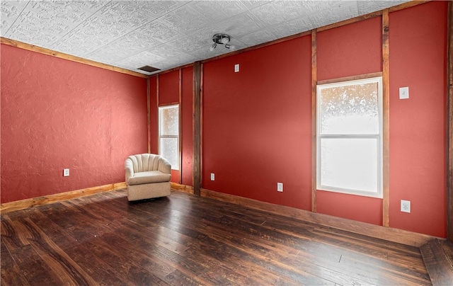 unfurnished room featuring baseboards, dark wood-type flooring, and a textured wall