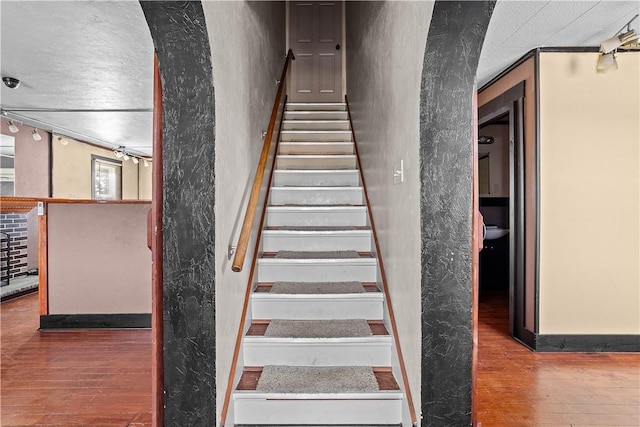 stairway with a textured wall and wood finished floors