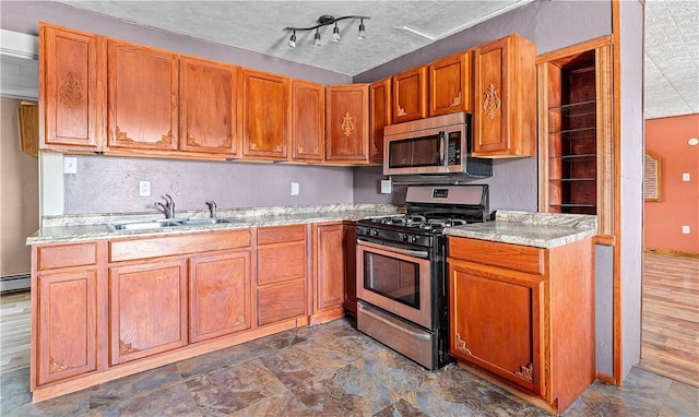 kitchen with brown cabinets, baseboard heating, a textured ceiling, stainless steel appliances, and a sink