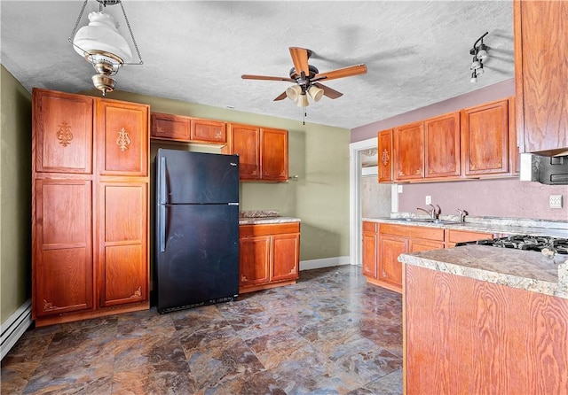 kitchen featuring light countertops, a baseboard heating unit, freestanding refrigerator, a sink, and ceiling fan