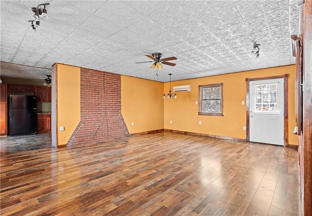 unfurnished living room with wood finished floors, ceiling fan, baseboards, and a wall mounted AC