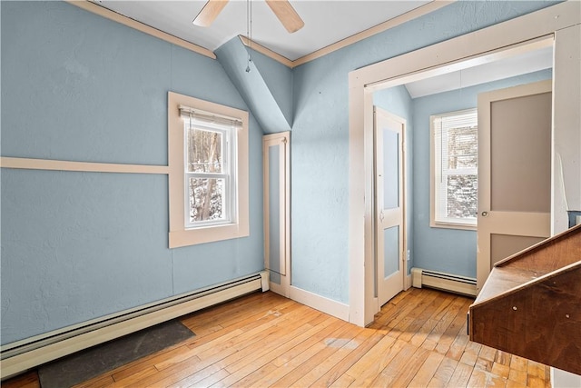 hallway with a wealth of natural light, baseboard heating, and light wood-style flooring