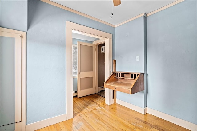 hallway featuring light wood finished floors, a baseboard radiator, baseboards, and crown molding