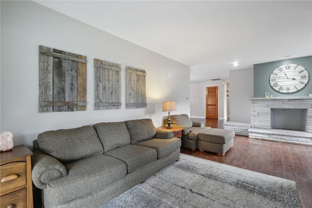 living room with wood-type flooring and a stone fireplace