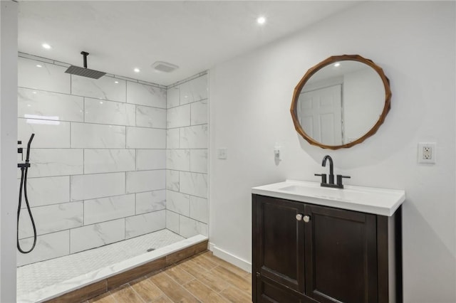 bathroom with a tile shower and vanity