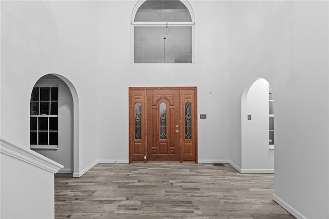 entryway featuring light hardwood / wood-style floors and a towering ceiling