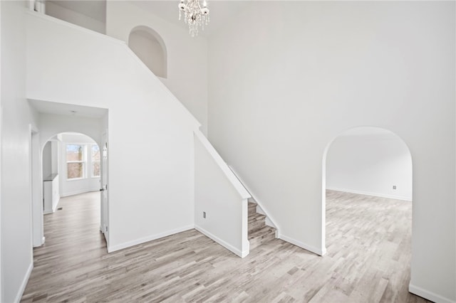 staircase with a notable chandelier, hardwood / wood-style floors, and a high ceiling