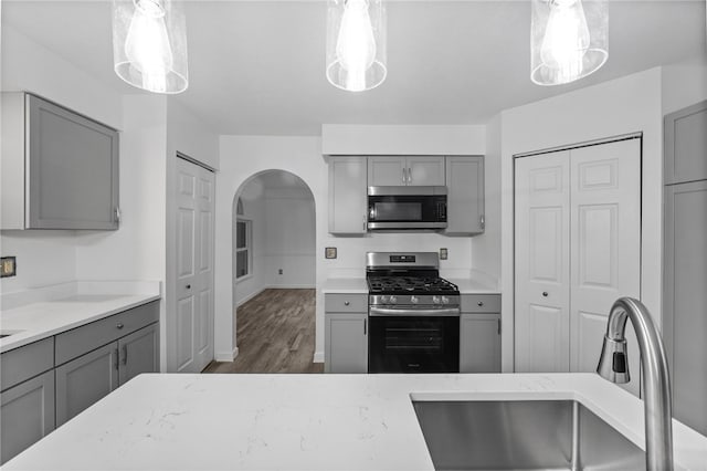 kitchen with gray cabinets, sink, pendant lighting, and appliances with stainless steel finishes