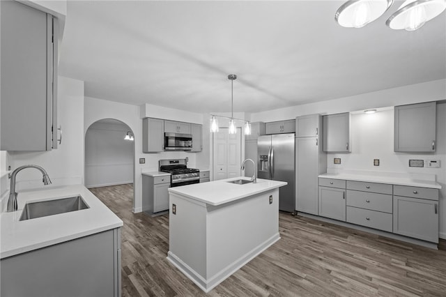 kitchen featuring gray cabinetry, a kitchen island with sink, sink, and appliances with stainless steel finishes