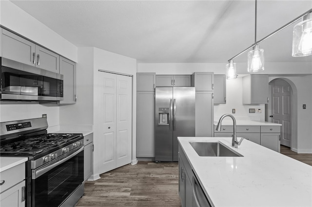 kitchen with stainless steel appliances, sink, gray cabinetry, and dark hardwood / wood-style floors