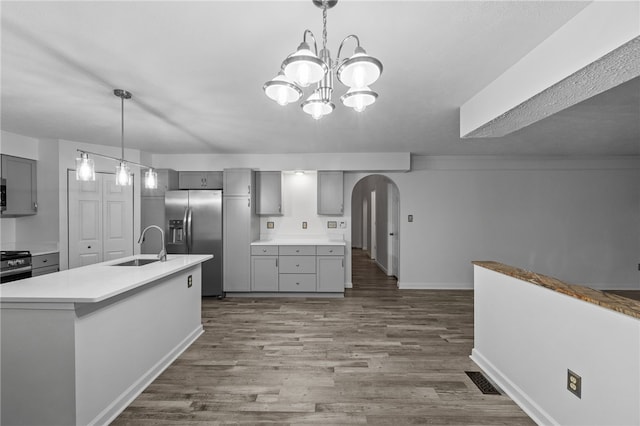 kitchen with an inviting chandelier, sink, stainless steel refrigerator with ice dispenser, hanging light fixtures, and gray cabinets