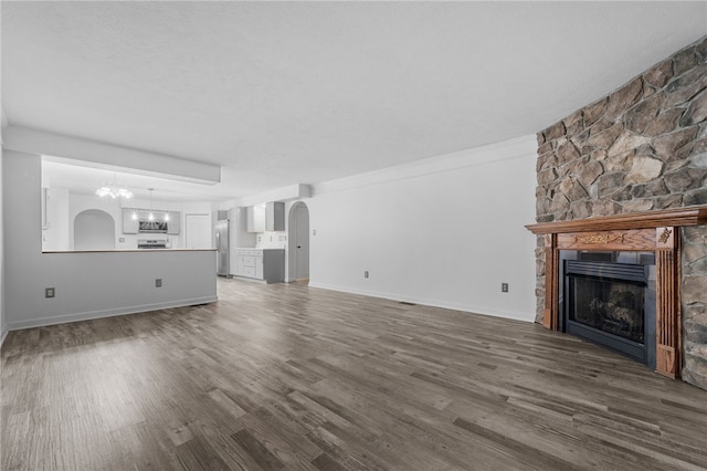 unfurnished living room with a fireplace, an inviting chandelier, dark wood-type flooring, and ornamental molding