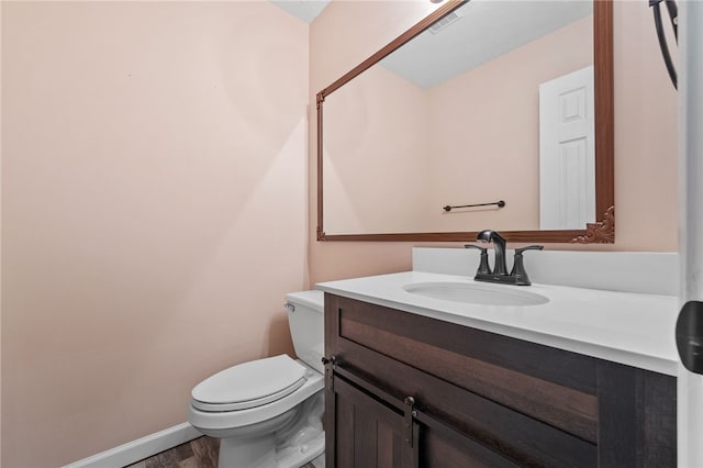 bathroom with hardwood / wood-style floors, vanity, and toilet