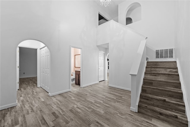 unfurnished living room featuring a towering ceiling and light hardwood / wood-style flooring