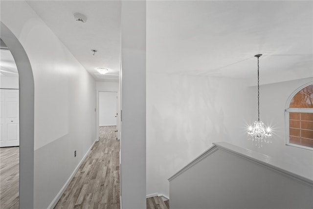 hall with a chandelier and light wood-type flooring