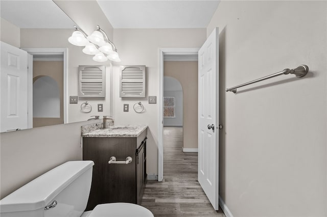 bathroom with wood-type flooring, vanity, and toilet