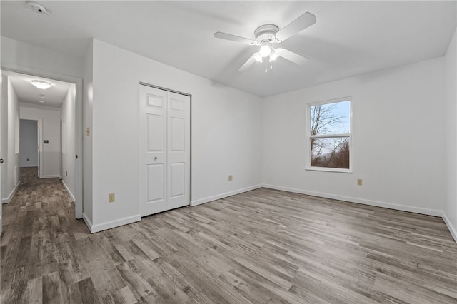 unfurnished bedroom with ceiling fan, light wood-type flooring, and a closet