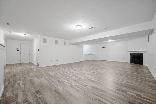 unfurnished living room featuring a textured ceiling and light hardwood / wood-style flooring