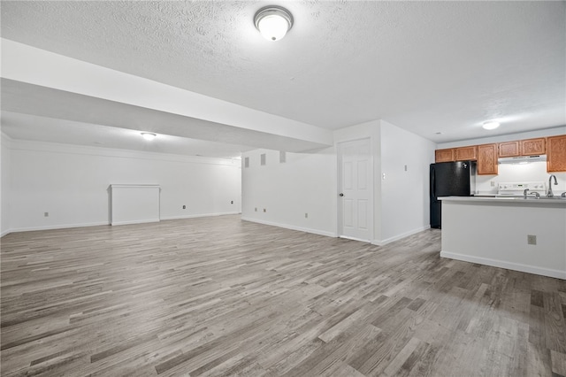 unfurnished living room featuring a textured ceiling and light hardwood / wood-style floors