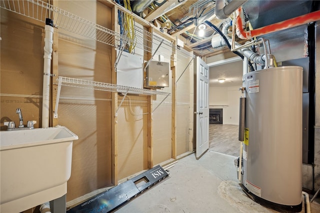 utility room featuring gas water heater and sink