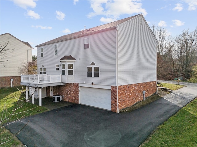 rear view of property with cooling unit, a garage, and a wooden deck