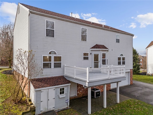 back of property with central air condition unit, a deck, and a garage