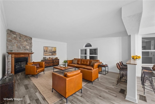 living room featuring crown molding, a fireplace, and light hardwood / wood-style floors