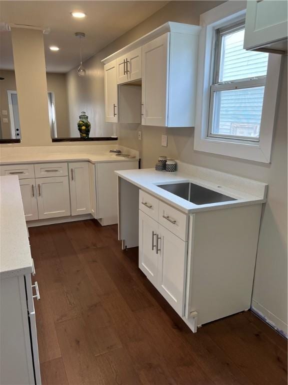 kitchen with dark wood-type flooring, white cabinets, and hanging light fixtures