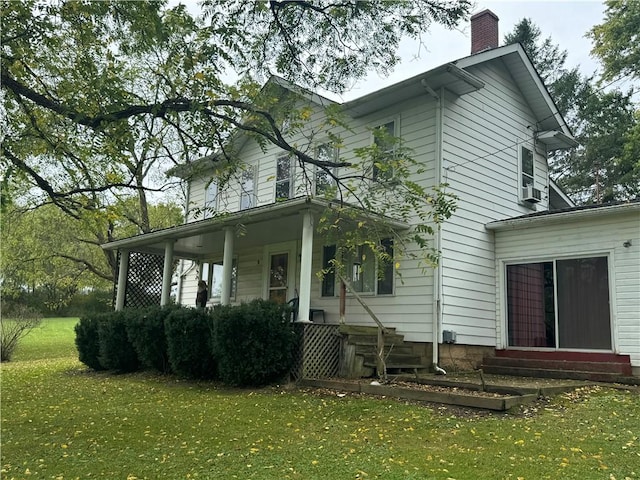 back of house featuring a yard and covered porch