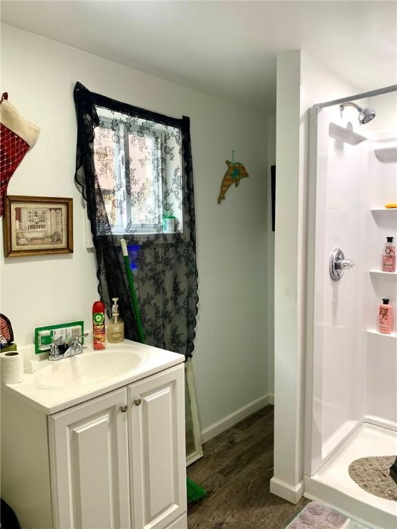 bathroom featuring hardwood / wood-style flooring, vanity, and a shower