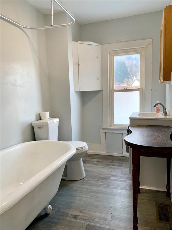 bathroom with hardwood / wood-style flooring, toilet, and a bathtub