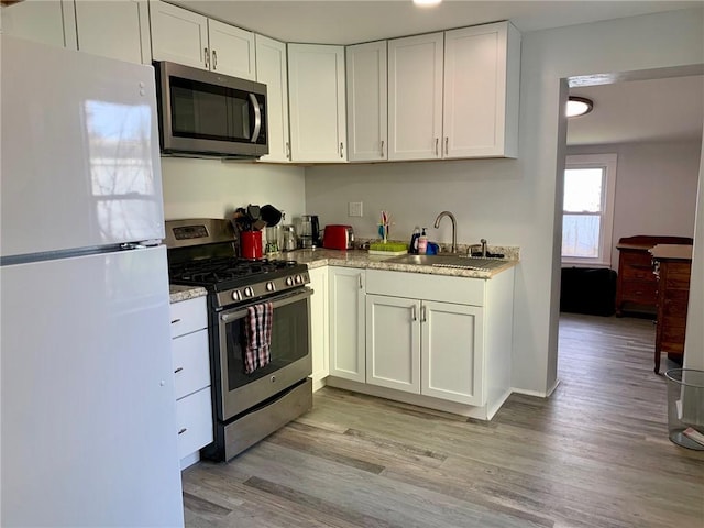 kitchen with white cabinetry, sink, appliances with stainless steel finishes, and light hardwood / wood-style flooring