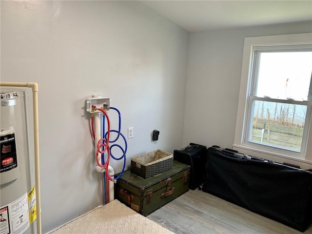 miscellaneous room with electric water heater and light hardwood / wood-style floors