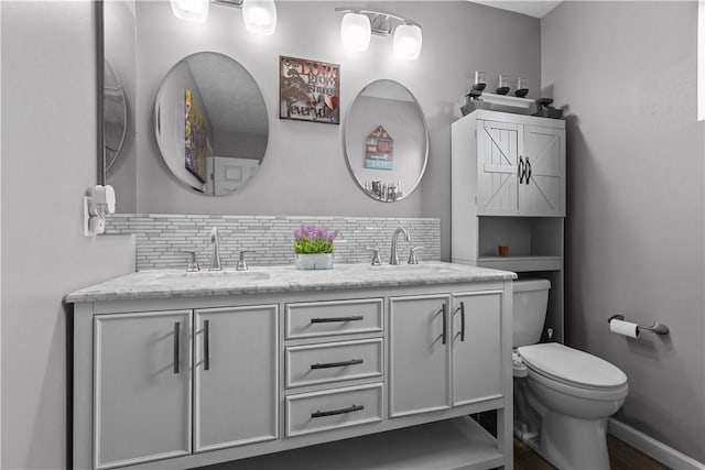 bathroom featuring vanity, backsplash, and toilet